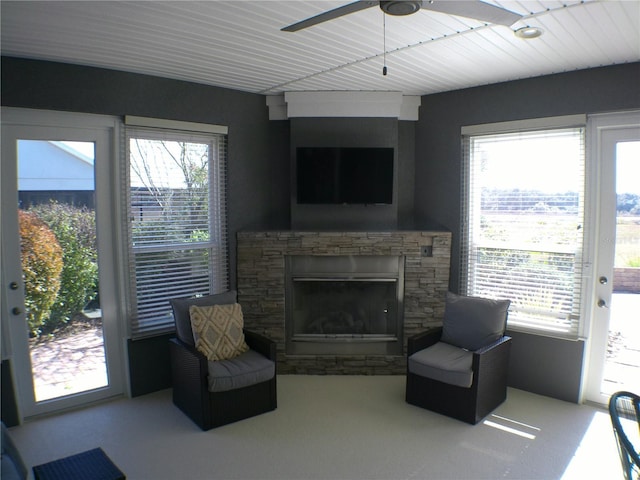 living room featuring plenty of natural light, a stone fireplace, and ceiling fan