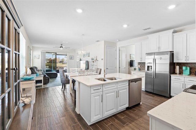 kitchen featuring appliances with stainless steel finishes, a kitchen island with sink, hanging light fixtures, and white cabinets