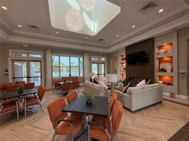 living room with a tray ceiling, built in shelves, french doors, and light parquet floors