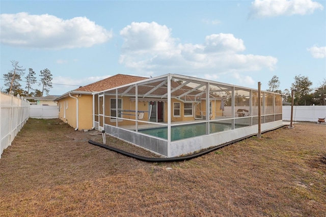 back of house with a fenced backyard, a lanai, a lawn, a fenced in pool, and stucco siding