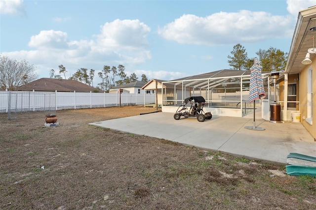 view of yard with glass enclosure, a fenced backyard, and a patio