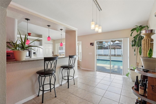 kitchen featuring a wealth of natural light, decorative light fixtures, a kitchen bar, and light tile patterned floors