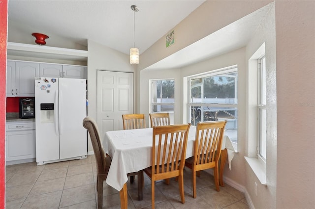 dining space with lofted ceiling, light tile patterned floors, and baseboards