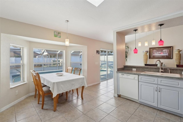 kitchen with light tile patterned floors, white dishwasher, a sink, hanging light fixtures, and dark countertops