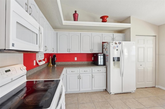 kitchen featuring white appliances, white cabinets, vaulted ceiling, and light tile patterned floors