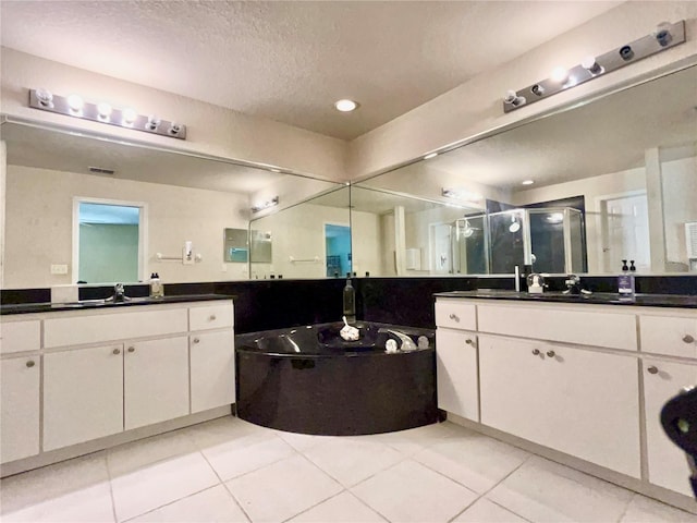 full bath with a garden tub, two vanities, a stall shower, a sink, and tile patterned floors