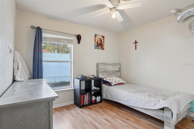 bedroom with light wood-style floors, ceiling fan, and baseboards