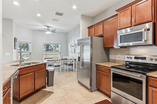 kitchen featuring light stone counters, appliances with stainless steel finishes, sink, and light tile patterned floors