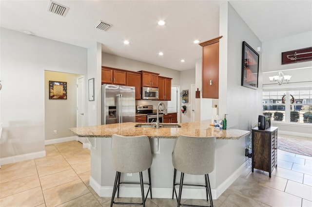 kitchen featuring sink, a breakfast bar area, light tile patterned floors, kitchen peninsula, and stainless steel appliances