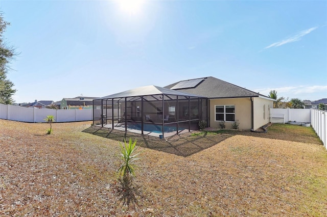 rear view of property featuring a fenced in pool and solar panels