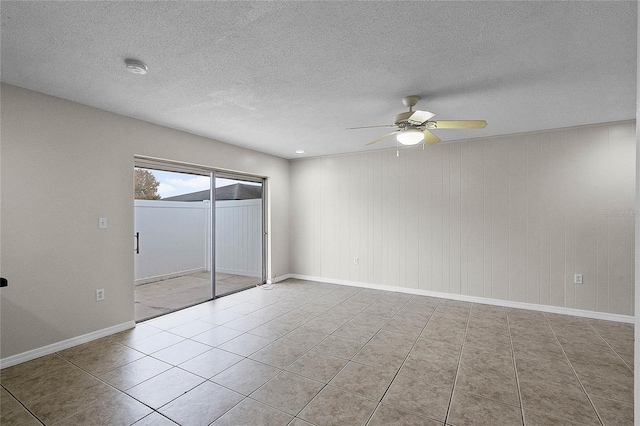 tiled spare room with a textured ceiling and ceiling fan