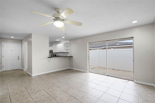 unfurnished living room featuring a textured ceiling, ceiling fan, and light tile patterned flooring