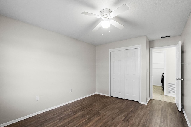 unfurnished bedroom with dark wood-type flooring, a textured ceiling, ceiling fan, and a closet