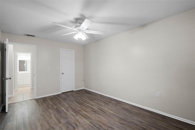 unfurnished bedroom featuring ceiling fan, dark hardwood / wood-style floors, and a textured ceiling