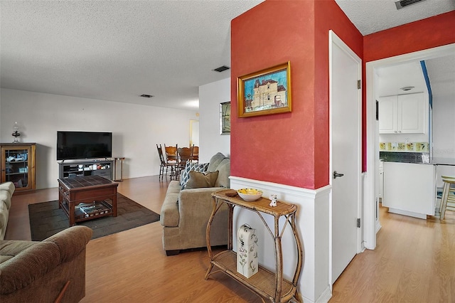 living room featuring a textured ceiling and light hardwood / wood-style flooring