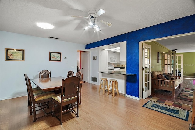 dining area featuring light wood finished floors, french doors, baseboards, visible vents, and ceiling fan