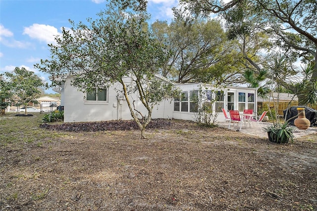 rear view of property with a patio area, a sunroom, and concrete block siding