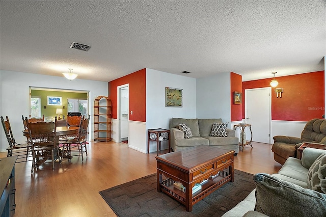 living room with wood finished floors, visible vents, and a textured ceiling