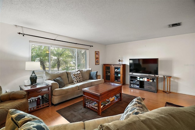 living room featuring a textured ceiling, wood finished floors, and visible vents
