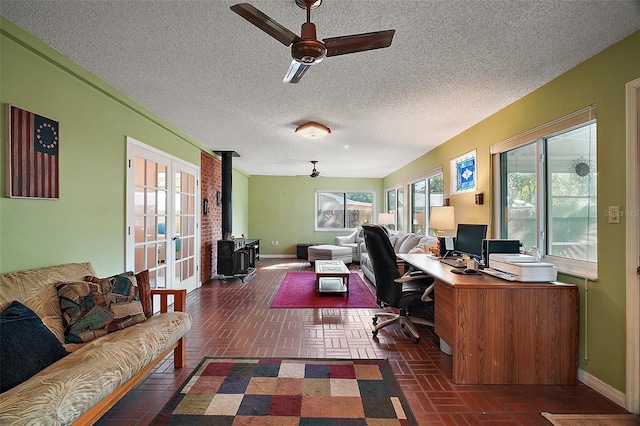 office with brick floor, a ceiling fan, baseboards, and a wood stove