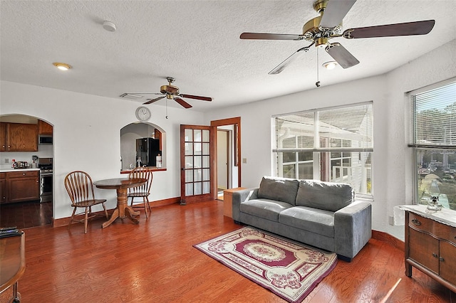 living room with dark hardwood / wood-style floors, a textured ceiling, and ceiling fan