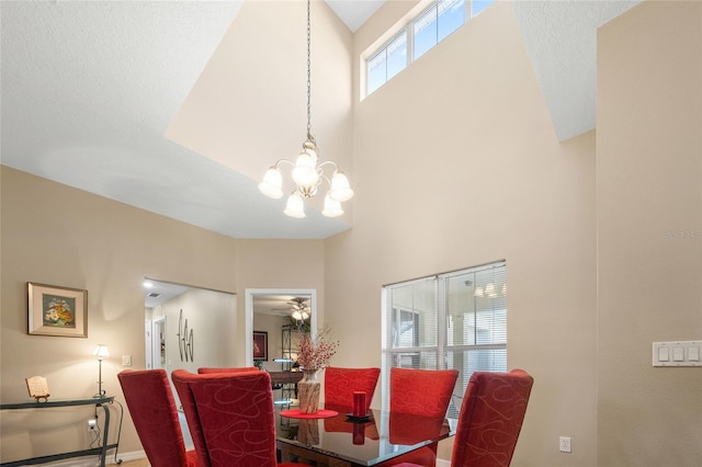 dining room with a towering ceiling and ceiling fan with notable chandelier