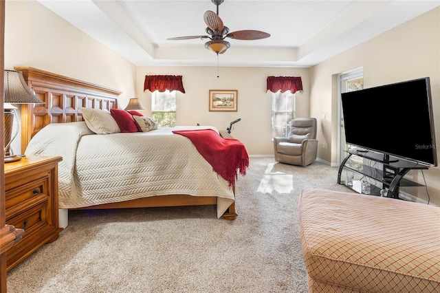 carpeted bedroom with ceiling fan and a tray ceiling