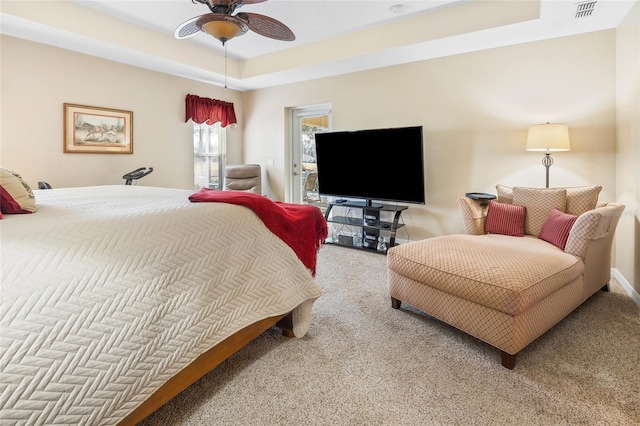 carpeted bedroom with a raised ceiling and ceiling fan