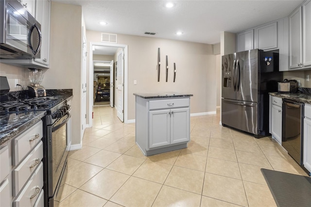 kitchen with stainless steel appliances, dark stone countertops, and light tile patterned floors