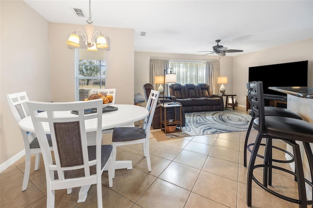 dining space with a healthy amount of sunlight, ceiling fan with notable chandelier, and light tile patterned floors