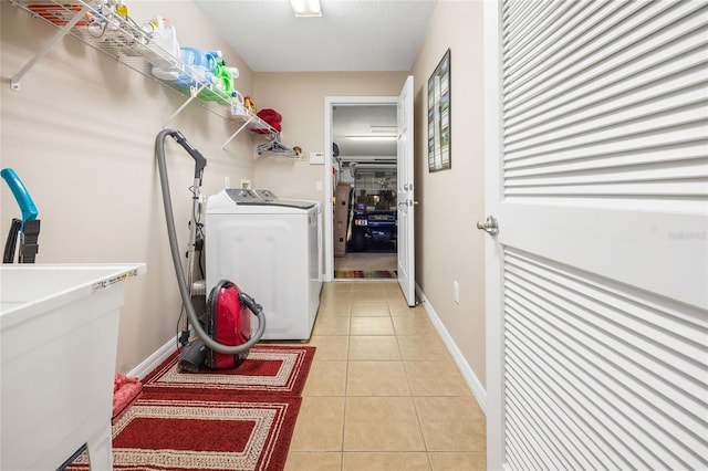 laundry area with sink, independent washer and dryer, and light tile patterned flooring