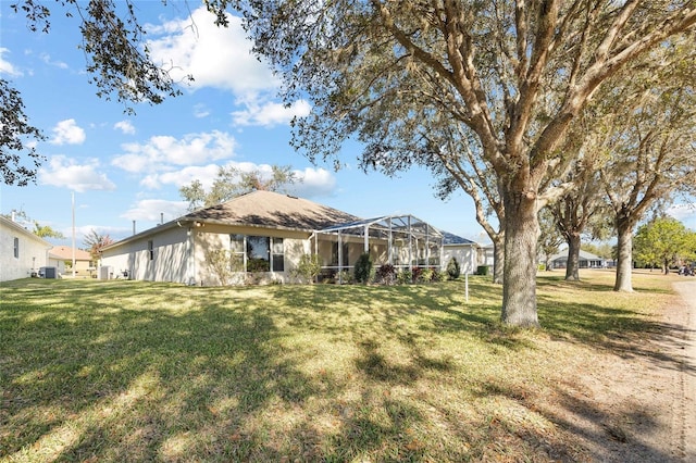 rear view of property featuring glass enclosure and a lawn