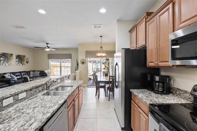 kitchen featuring pendant lighting, sink, light tile patterned floors, appliances with stainless steel finishes, and light stone countertops