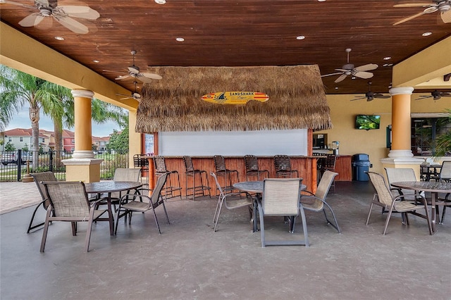 view of patio with ceiling fan and a bar