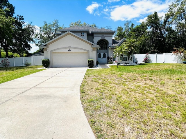 mediterranean / spanish-style house with driveway, fence, an attached garage, a front yard, and stucco siding