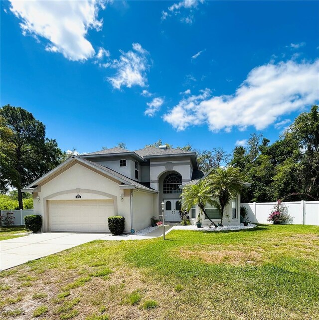 mediterranean / spanish-style house featuring fence, a front lawn, stucco siding, concrete driveway, and a garage