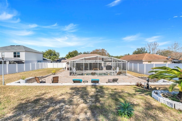 back of house with a pool, a lanai, a patio area, and a yard