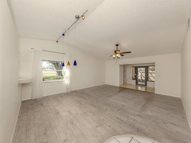 unfurnished living room with ceiling fan, track lighting, a textured ceiling, vaulted ceiling, and light wood-type flooring