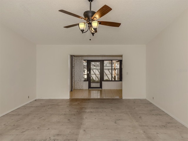 empty room featuring ceiling fan, light hardwood / wood-style flooring, and a textured ceiling