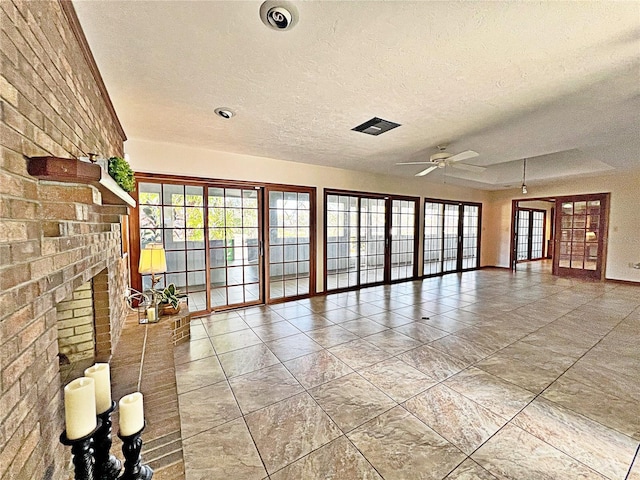 unfurnished living room with ceiling fan, a healthy amount of sunlight, tile patterned flooring, and a textured ceiling