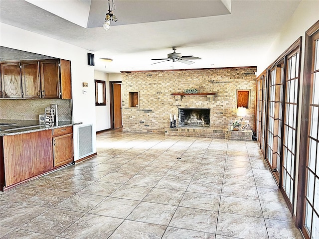 kitchen with decorative light fixtures, ceiling fan, brick wall, a fireplace, and backsplash