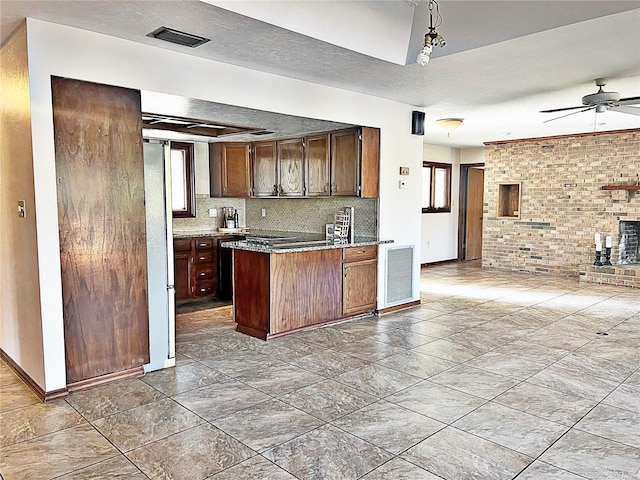 kitchen with ceiling fan, refrigerator, backsplash, a textured ceiling, and brick wall