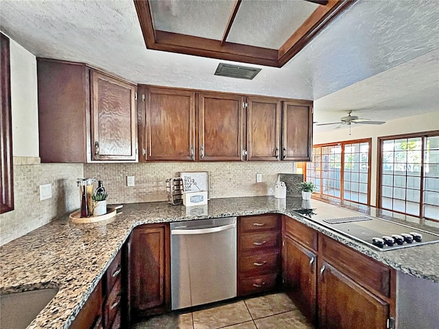 kitchen with electric cooktop, stainless steel dishwasher, dark stone counters, and a textured ceiling