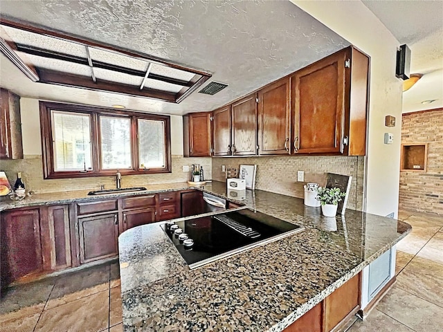 kitchen with sink, tasteful backsplash, a textured ceiling, dark stone counters, and black electric stovetop