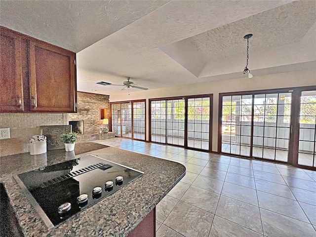 kitchen featuring black electric stovetop, a healthy amount of sunlight, a brick fireplace, and a textured ceiling