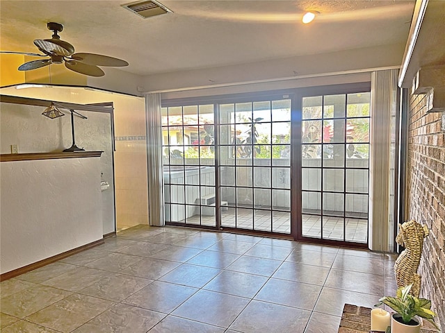 doorway featuring ceiling fan, a healthy amount of sunlight, tile patterned floors, and a textured ceiling