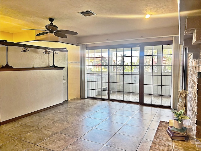 interior space with ceiling fan, tile patterned floors, and a textured ceiling