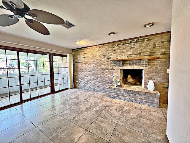 unfurnished living room featuring ceiling fan, brick wall, and a brick fireplace