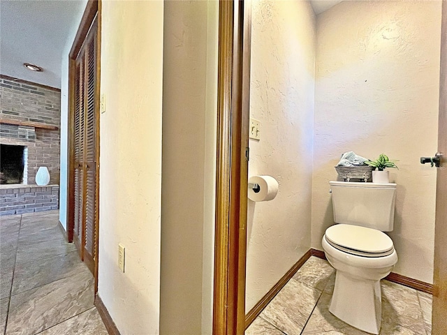 bathroom with a brick fireplace, toilet, and brick wall