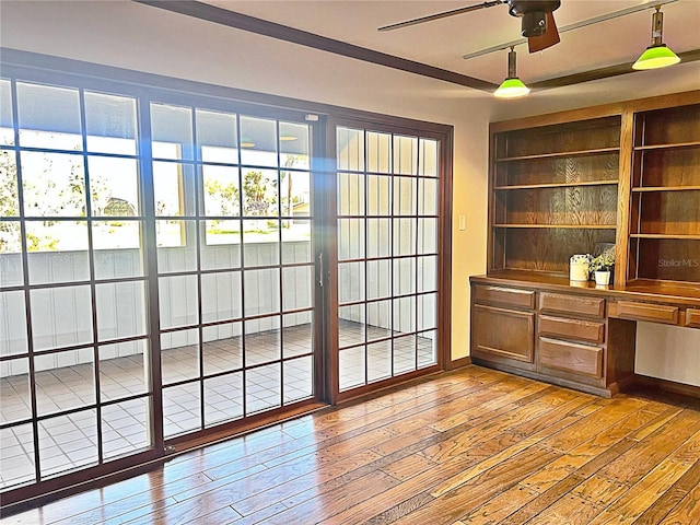 interior space featuring ceiling fan, built in desk, and wood-type flooring